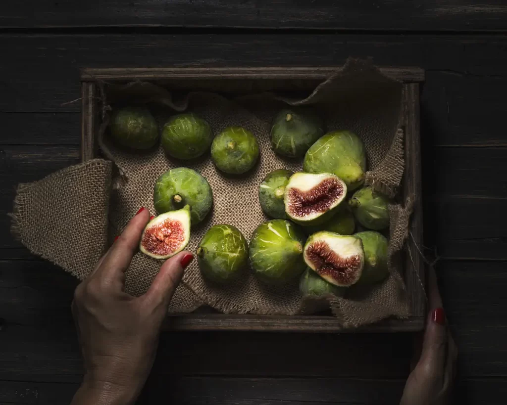 Des figues dans une caisse. Certaines sont ouvertes et une est tenue par une main