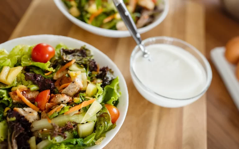 Une assiette de salade posée à côté d'une sauce blanche