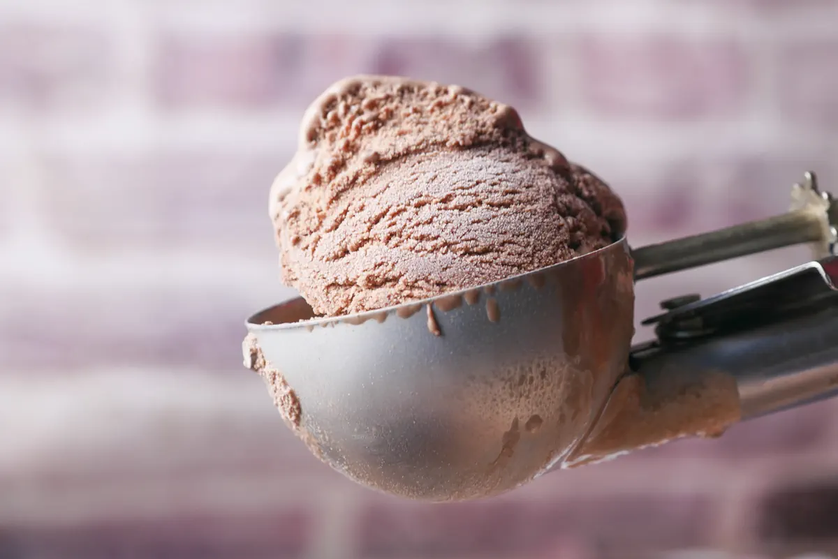 Une boule de glace à l'eau marron dans une cuillère en métal