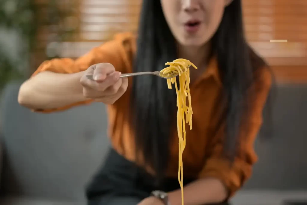 Une femme qui mange des pâtes