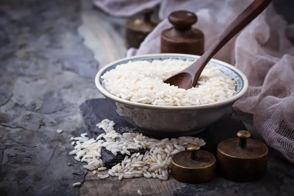 Un bol de riz blanc posé sur une table avec une cuillère en bois